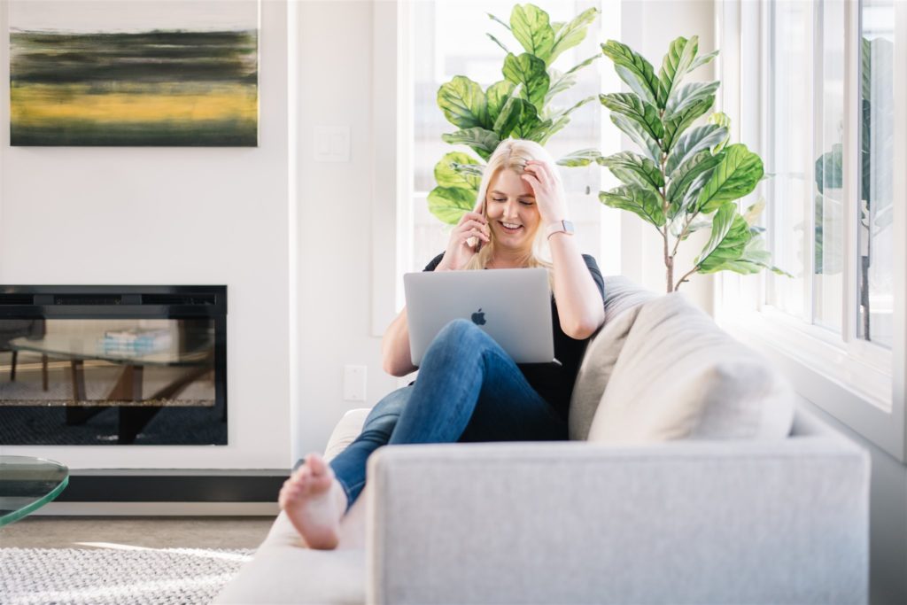 Blonde woman posing on couch with laptop for a regular branding session