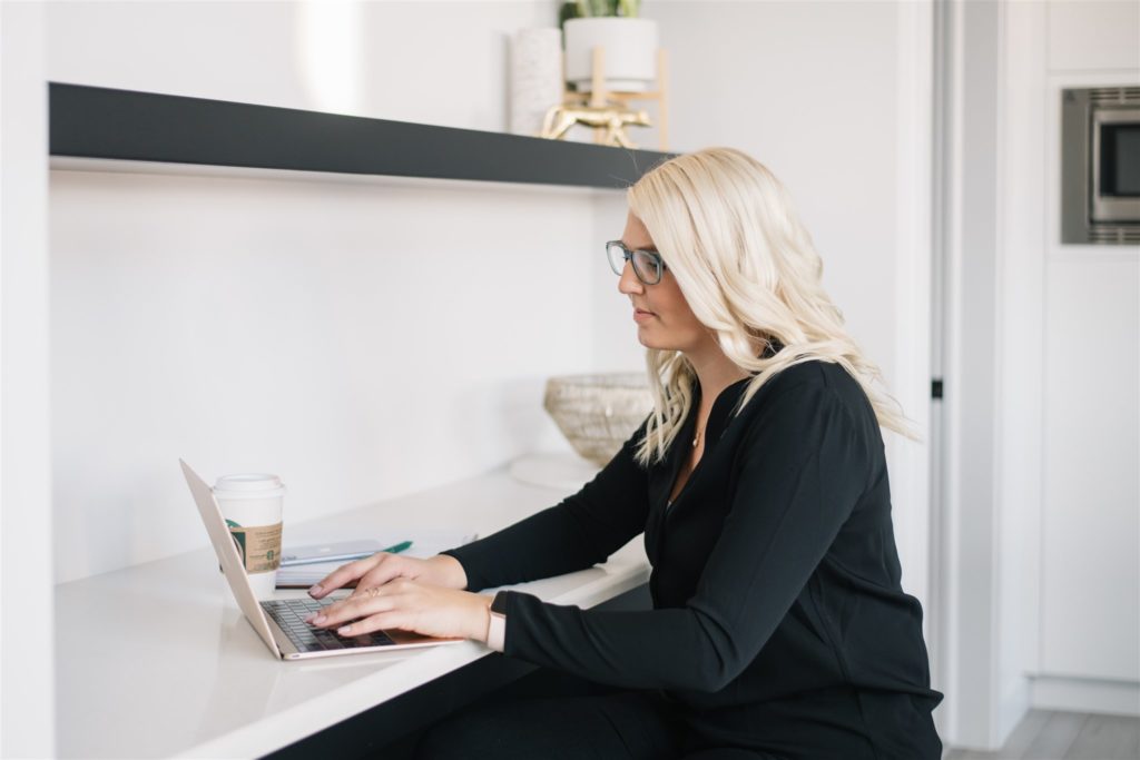 Blonde woman working on a laptop with a coffee during a monthly branding session