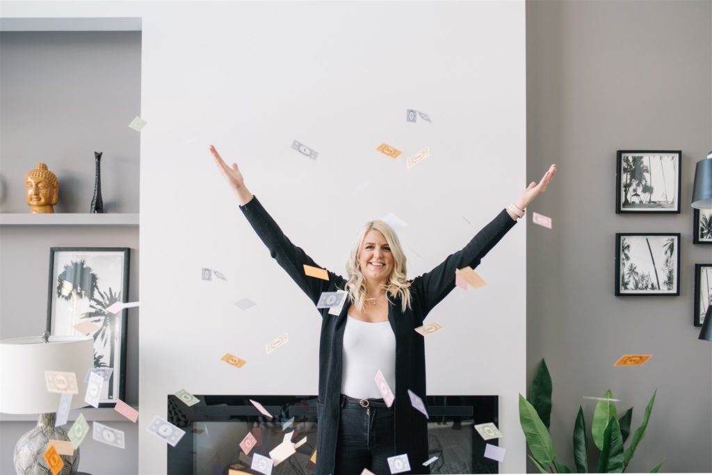 Blonde woman throws monopoly money in the air during a regular branding session