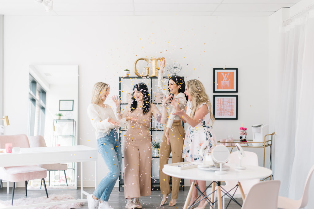Four women pop confetti to celebrate in their office