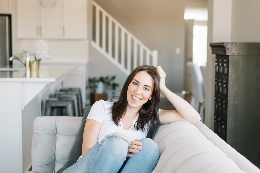 A woman sits on her couch with blue jeans on
