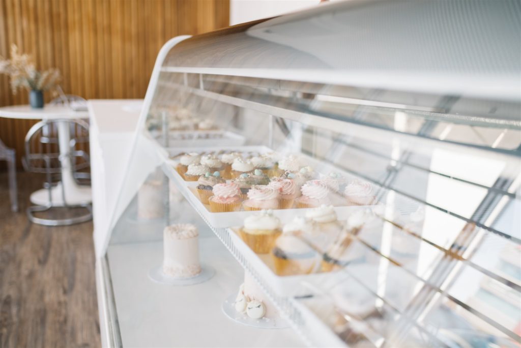 rows of cupcakes inside a display case at a dessert store