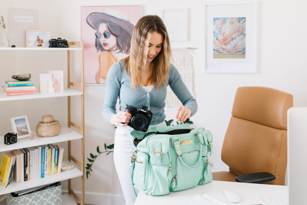 Woman packing her professional nikon camera into a baby blue camera bah