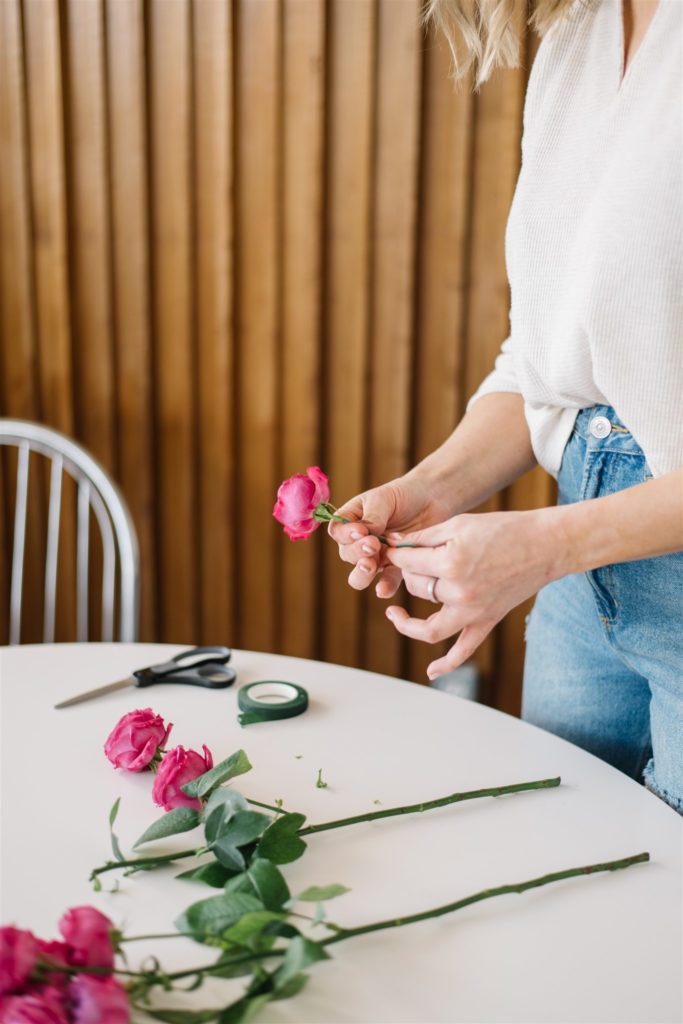 woman cutting the stems off of roses