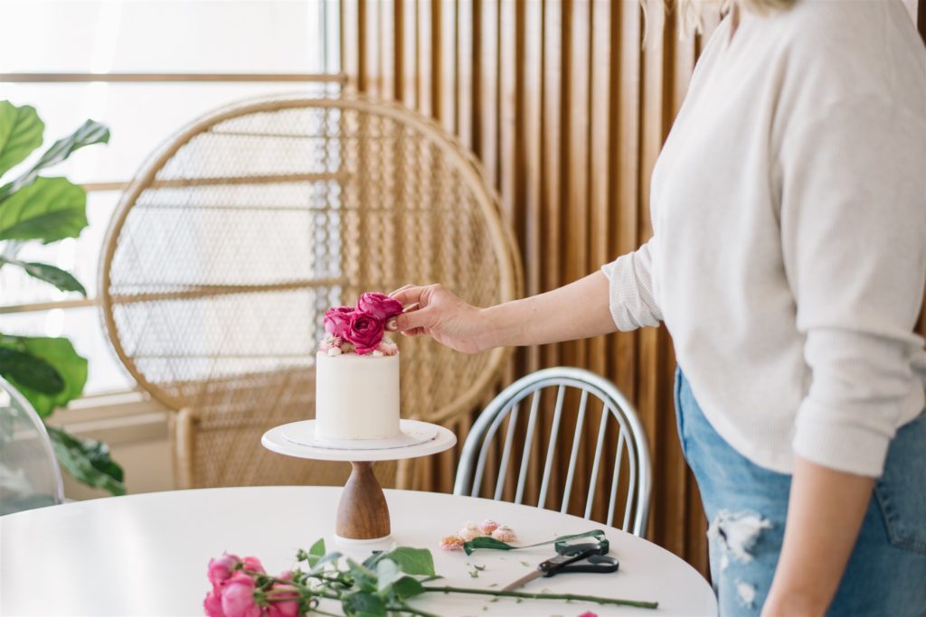 Edmonton wedding cake designer placing rose on top of cake