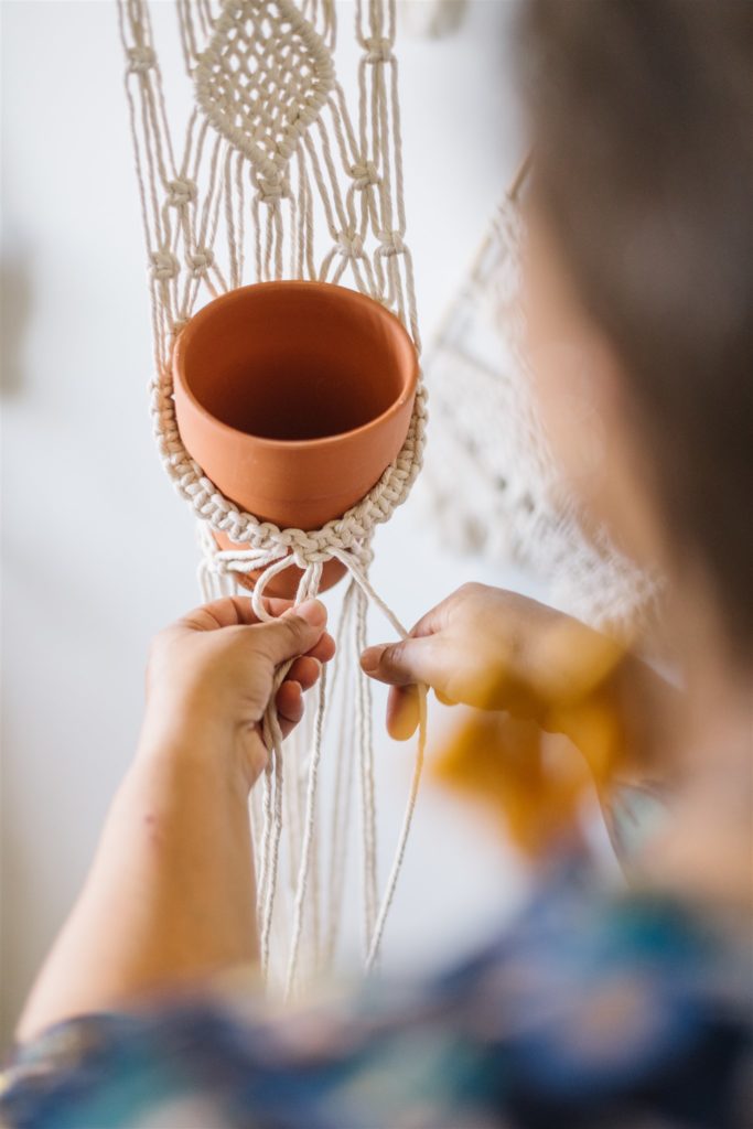 view from over the shoulder of hands tying a macramé plant pot holder