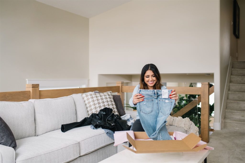 woman unboxing a pair of jeans in her living room