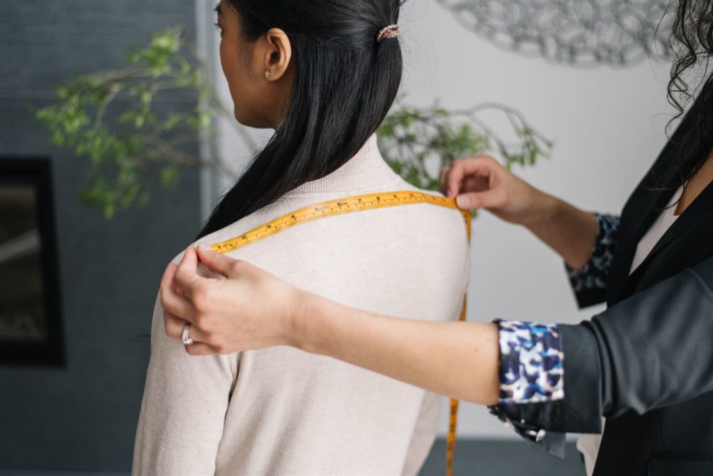 woman measuring the shoulders of another woman at a seamstress branding photoshoot