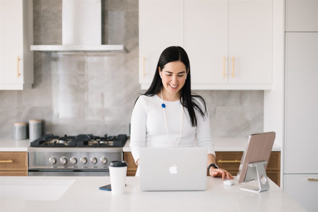 woman learning how to pose with your laptop during a branding photoshoot in a kitchen