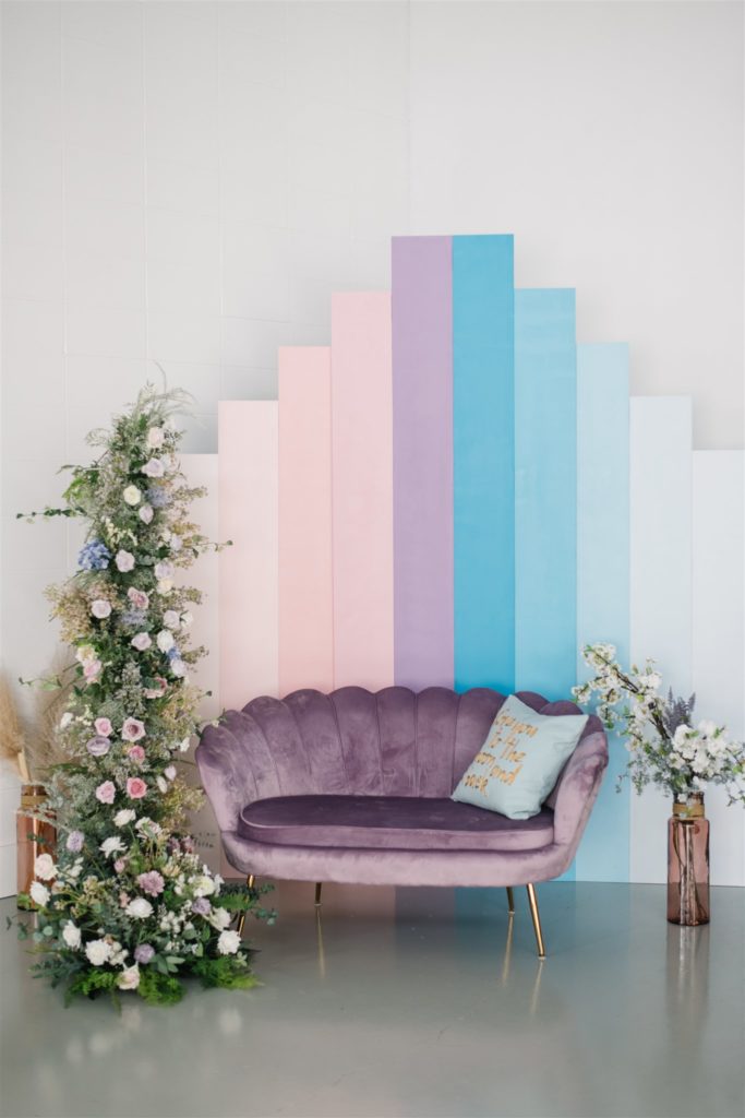 purple velvet couch in front of pastel wall