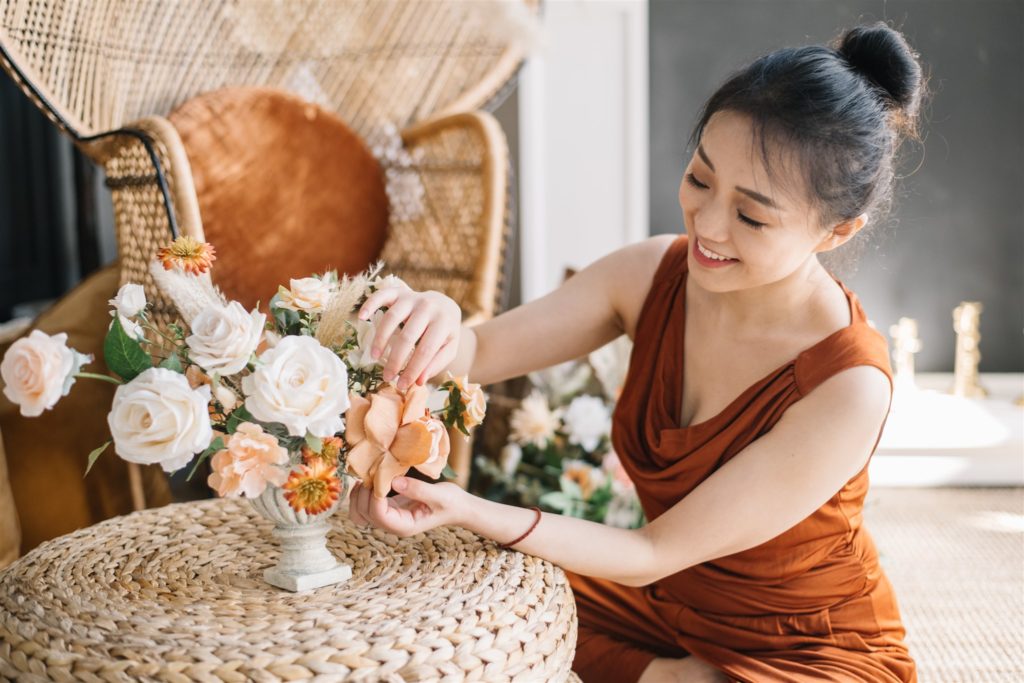 woman arranging faux florals in a vase
