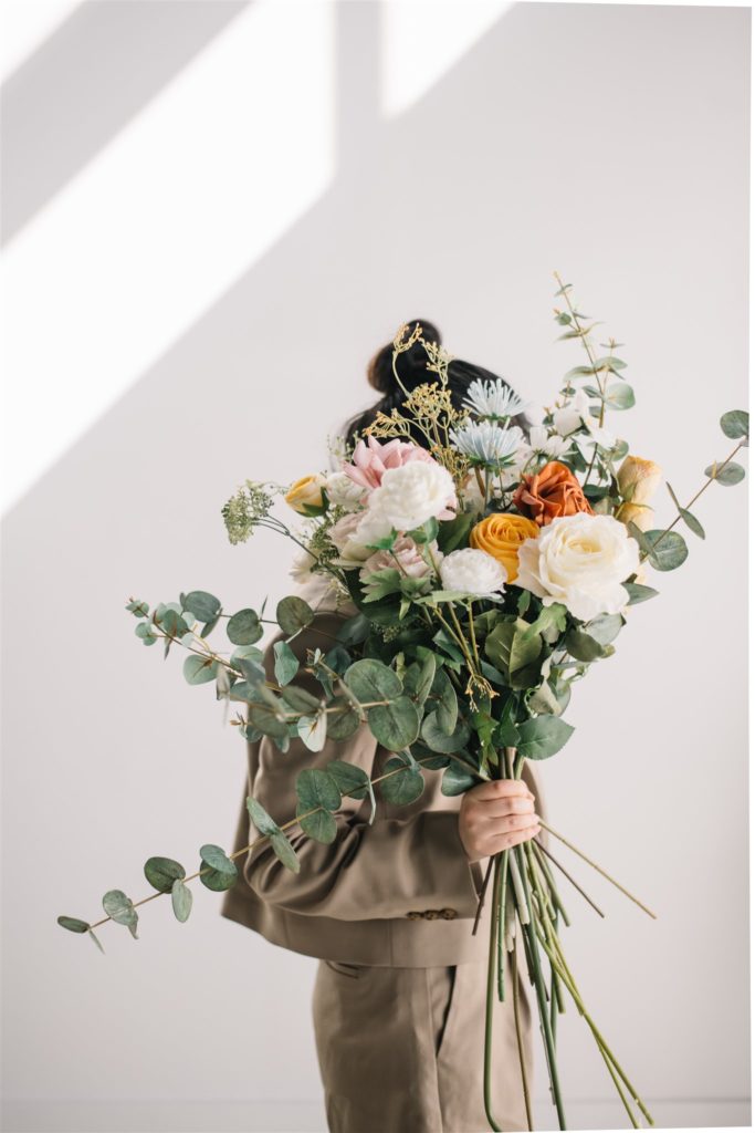 woman holding faux floral bouquet in front of her face