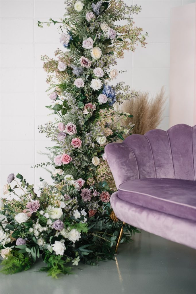 tower of flowers beside an antique purple velvet couch