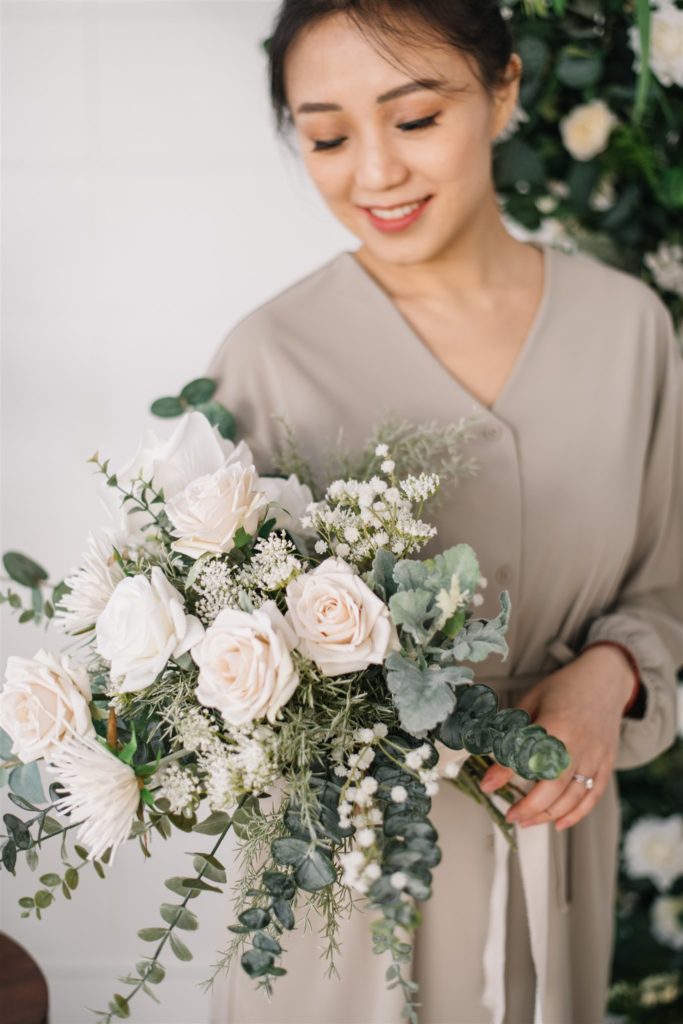 woman holding a bouquet of white roses and eucalyptus