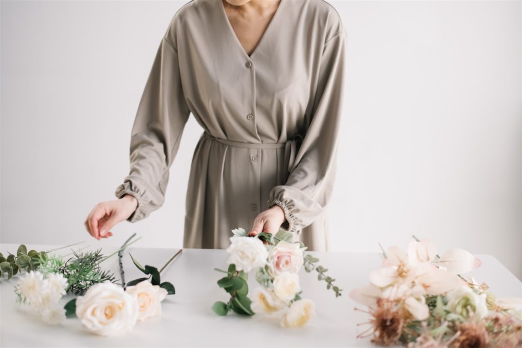 woman picking flowers off a table to create an arrangement