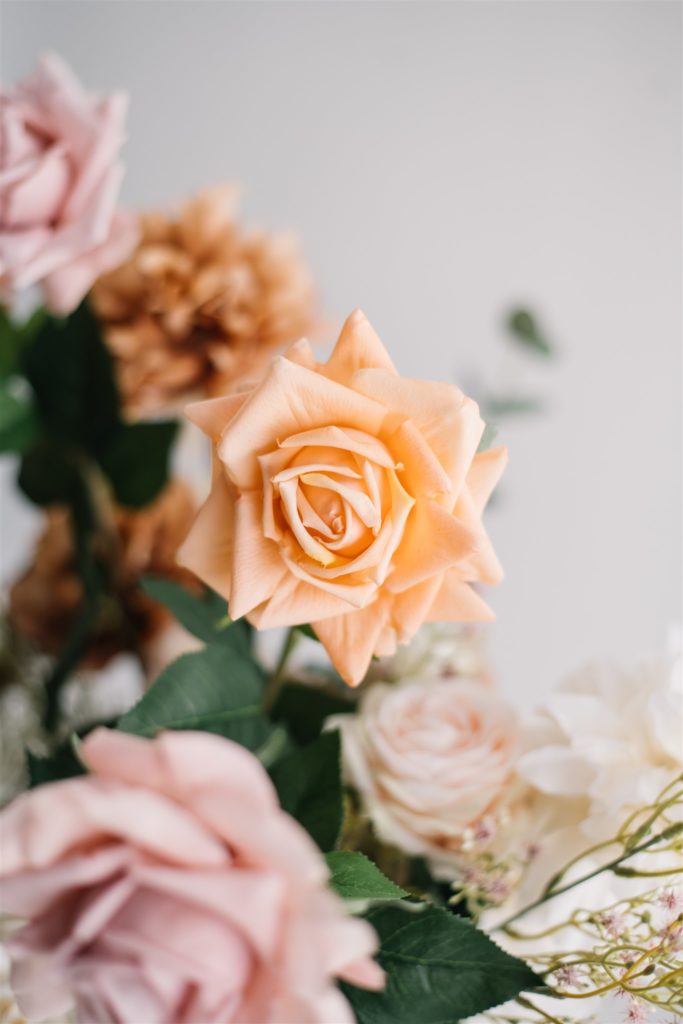 up close photo of an orange rose amidst a bouquet 