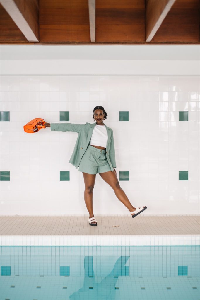 Woman dressed in a professional summer outfit standing beside a pool