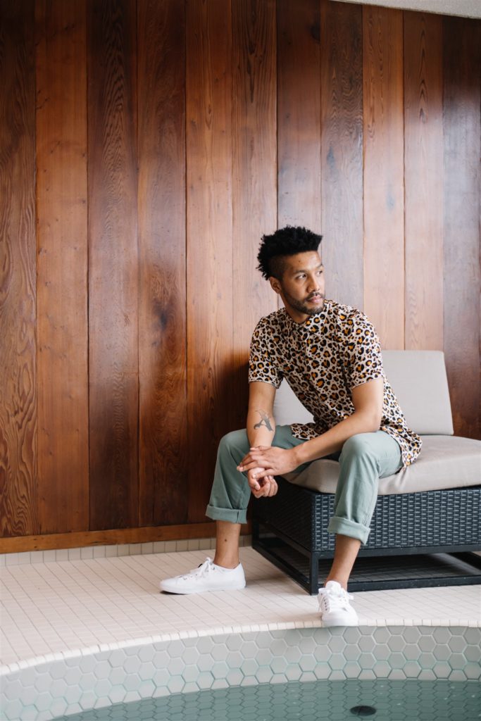 Man sitting on a lounge chair wearing a leopard print shirt and blue jeans