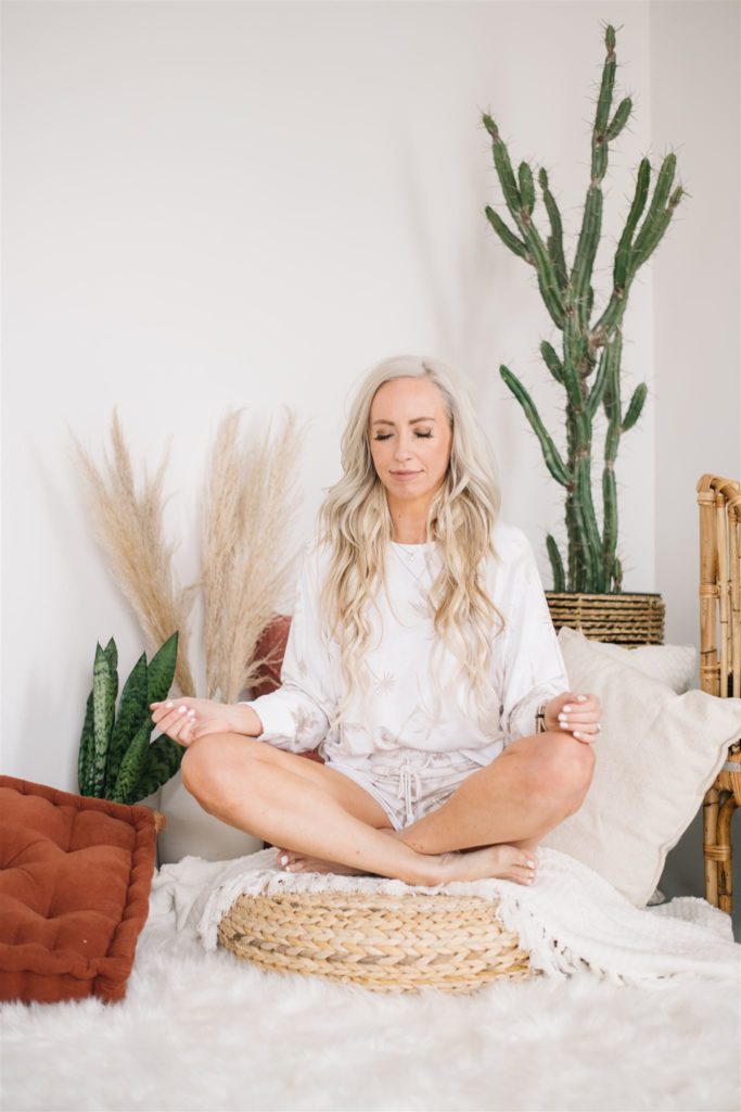 woman sitting cross-legged and meditating as a form of self-care