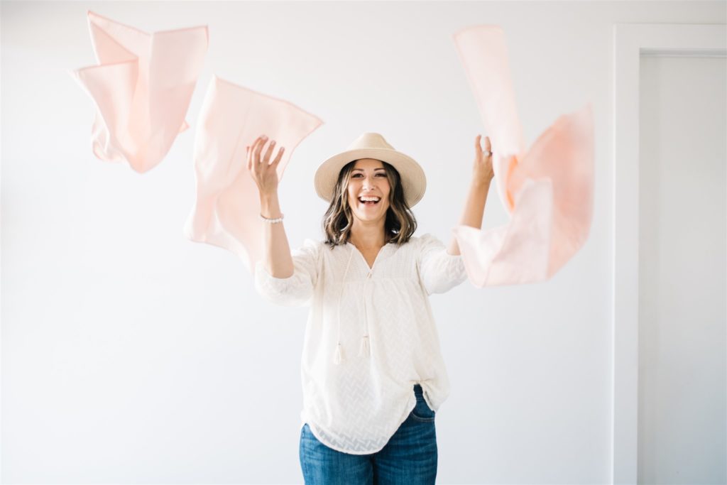 A woman throws pink napkins at the camera during her branding session